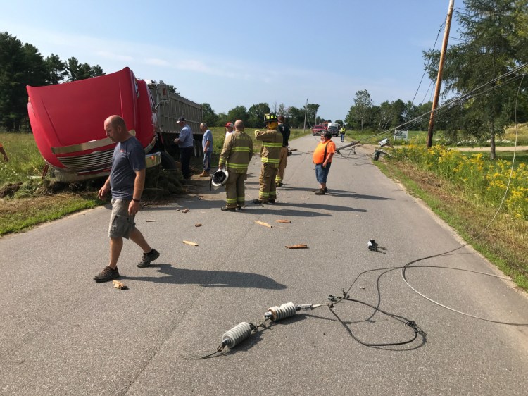 An emergency crew surveys the scene Wednesday morning on Vigue Road in Whitefield after a tractor-trailer crashed, knocking over utility lines.