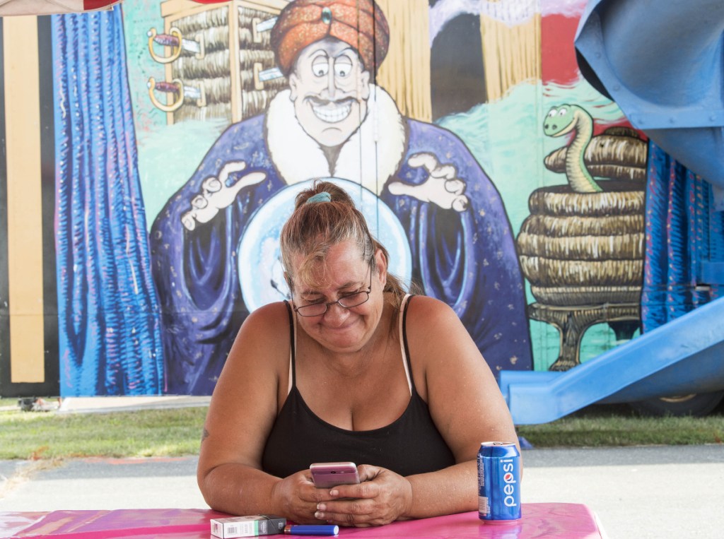 Gayle Palombo, a worker with Fiesta Shows, takes a break in front of the fun house as crews set up for the 200th annual Skowhegan State Fair at the Skowhegan Fair Grounds on Wednesday.