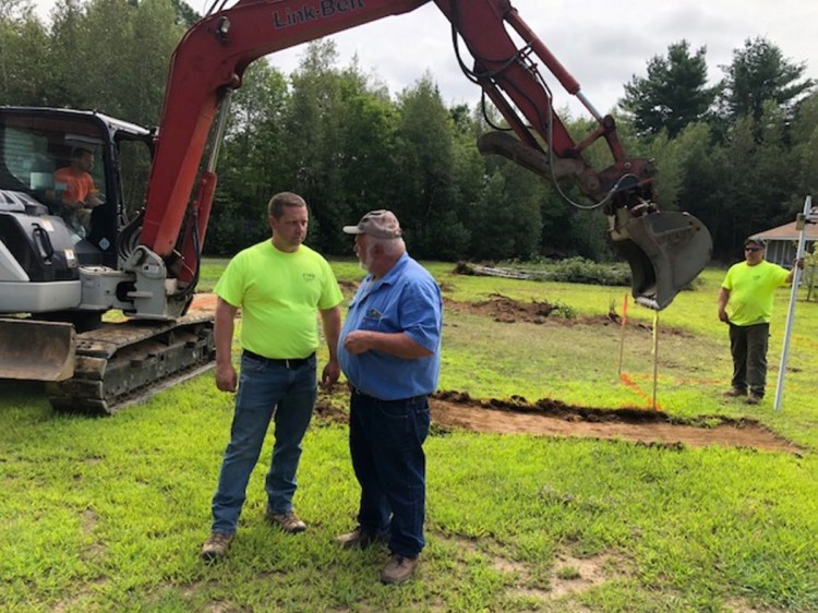 Mickey Wing, right, of Central Maine Disposal and Excavation, confers with Joel Violette, of Fairfield Drafting & Construction, over plans for a new home for Sheryl Cole.
