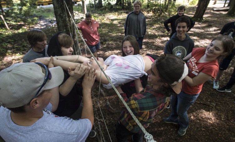 Abby Partridge, a student at MeANS Good-Will Hinckley school, is lifted and passed through the spider web initiative with the help of classmates on Sept. 8, 2017, at Camp Tracy in Oakland.