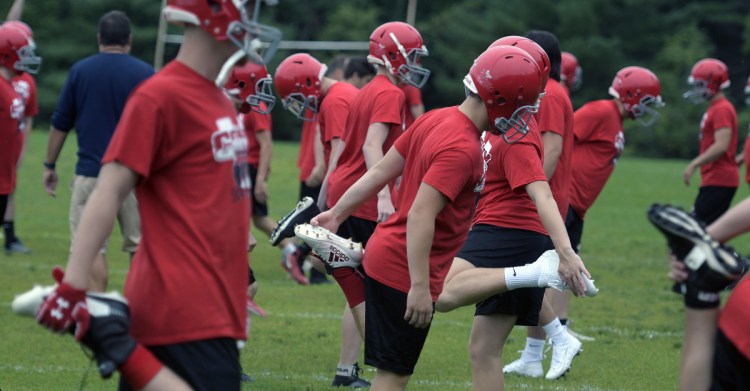 Cony High School football players work through some stretching drills during practice Monday morning in Augusta. Monday marked the first day fall sports teams could start practicing.