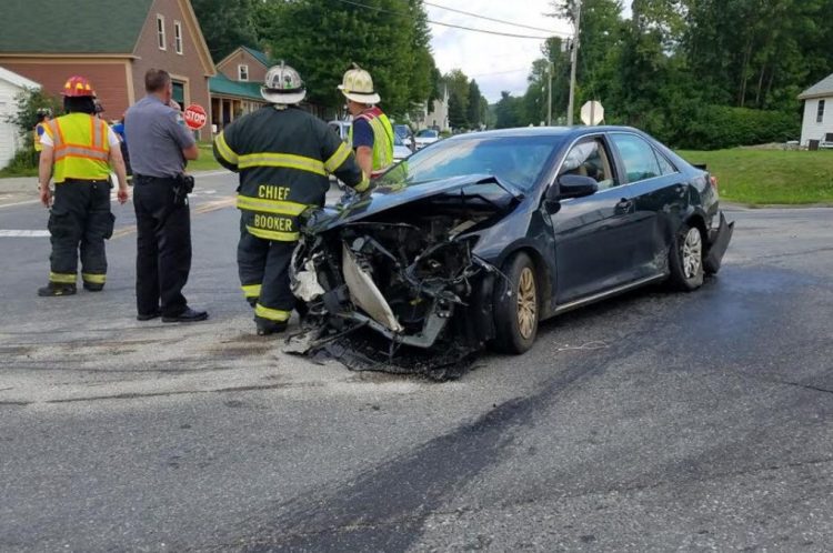 Firefighters and a police officer stand next to a car driven by Adelle Foss, 17, of Farmington, who was injured Wednesday afternoon in a three-vehicle collision at routes 133 and 156. She was taken to a local hospital for treatment of minor injuries.