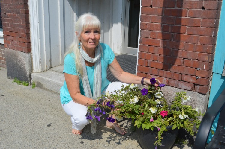 Susun Terese, owner of Minikins on Broadway in Farmington, crouches next to one of her planters on Friday that was tipped over during a vandalism spree that struck the downtown area and the University of Maine at Farmington campus in the early morning hours.