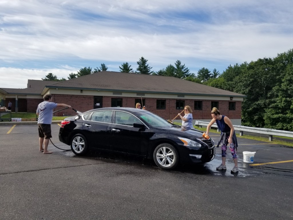 Individuals washing black car from left are Ben Roberts, compliance officer and training specialist; Kim Turner, president/CEO; Stephanie Nichols, cards specialist; and Alicia Fanjoy, teller, all with OTIS Federal Credit Union in Jay.