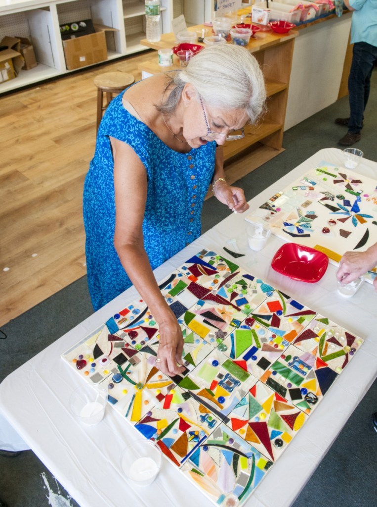 Carolyn Downing adds a piece of glass to the community mosaic art project during annual Winthrop Arts Festival on Saturday in downtown Winthrop. The panels will be displayed in a town hall meeting room when completed.