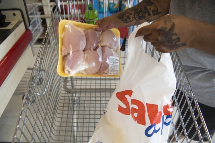 Greg Oullette bags his own groceries with a plastic bag after shopping at Save-A-Lot in Waterville on Wednesday.