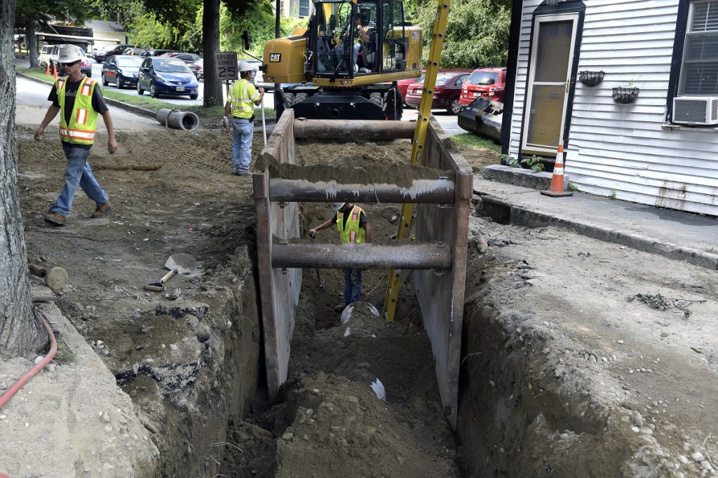 Sargent Corporation workers set a pipe at the intersection of Water and Academy streets in Hallowell Monday as part of the Maine Department of Transportation's reconstruction of Route 201 Project.