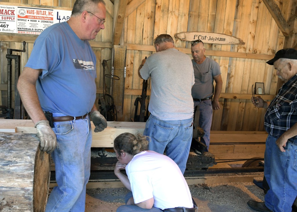 Volunteers attempt to fix the saw mill Sunday at the Windsor Fairgrounds after it malfunctioned.