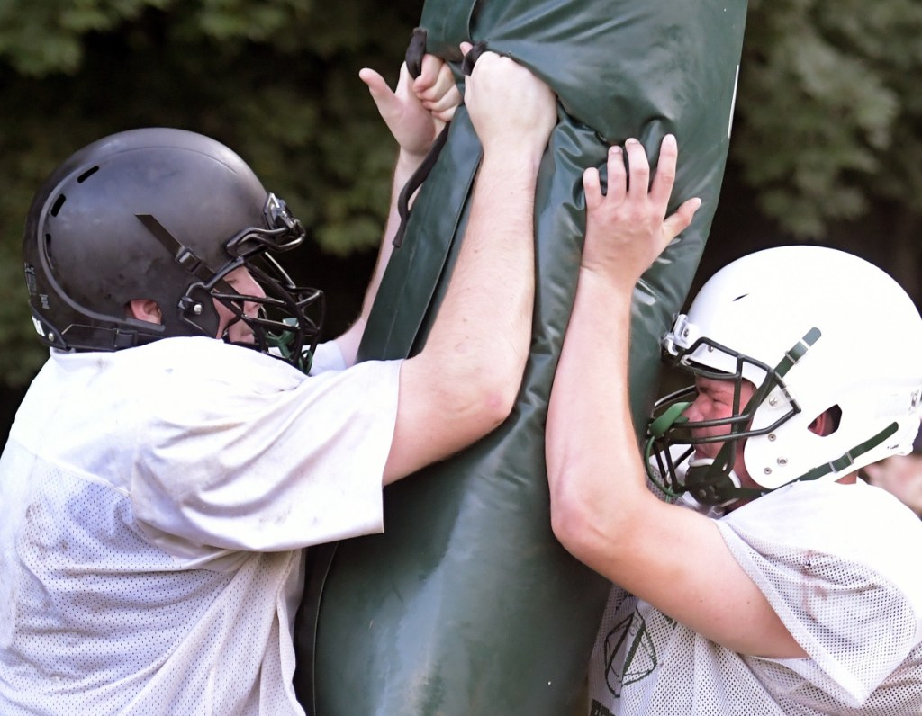 Hall-Dale High School's Patrick Rush, left, and Alixx Canwell pound a football pad during a recent practice in Winthrop.