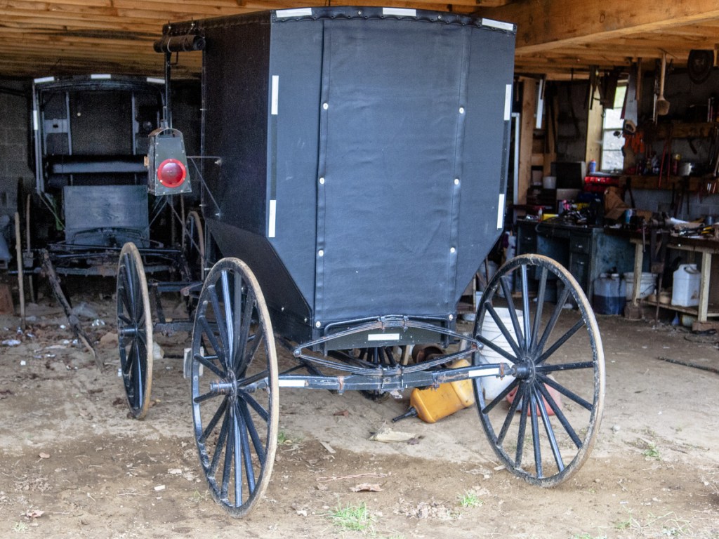 Several buggies with white reflective tape stand parked in a barn on Oct. 31, 2017, at the Hostetler family's farm on in Whitefield.