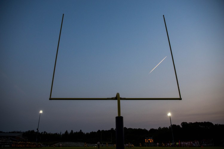 A jet's vapor trail splits the goal posts at Caldwell Field on the Mt. Blue High School campus in Farmington during an Aug. 24 preseason game between the Cougars and Cony Rams.