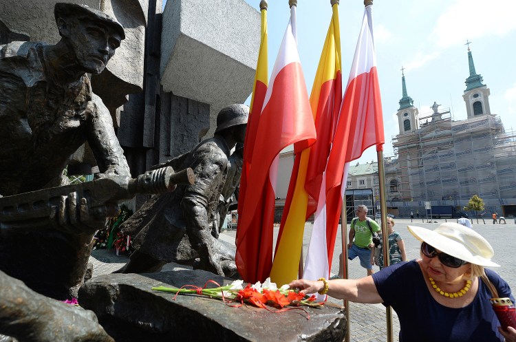 Warsaw residents lay flowers Wednesday at the monument to the 1944 Warsaw Rising against the occupying Nazis to honor some 18,000 resistance fighters who fell in the struggle against the German forces and some 180,000 civilians who perished 74 years ago, in Warsaw, Poland.