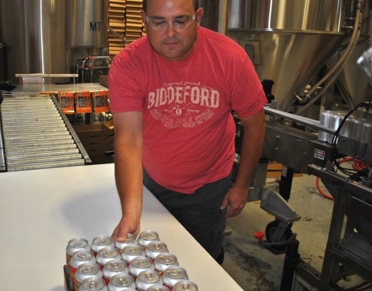 Biddeford firefighter Tim Sevigny guides a case of beer across a table Tuesday morning at Dirigo Brewing in Biddeford.