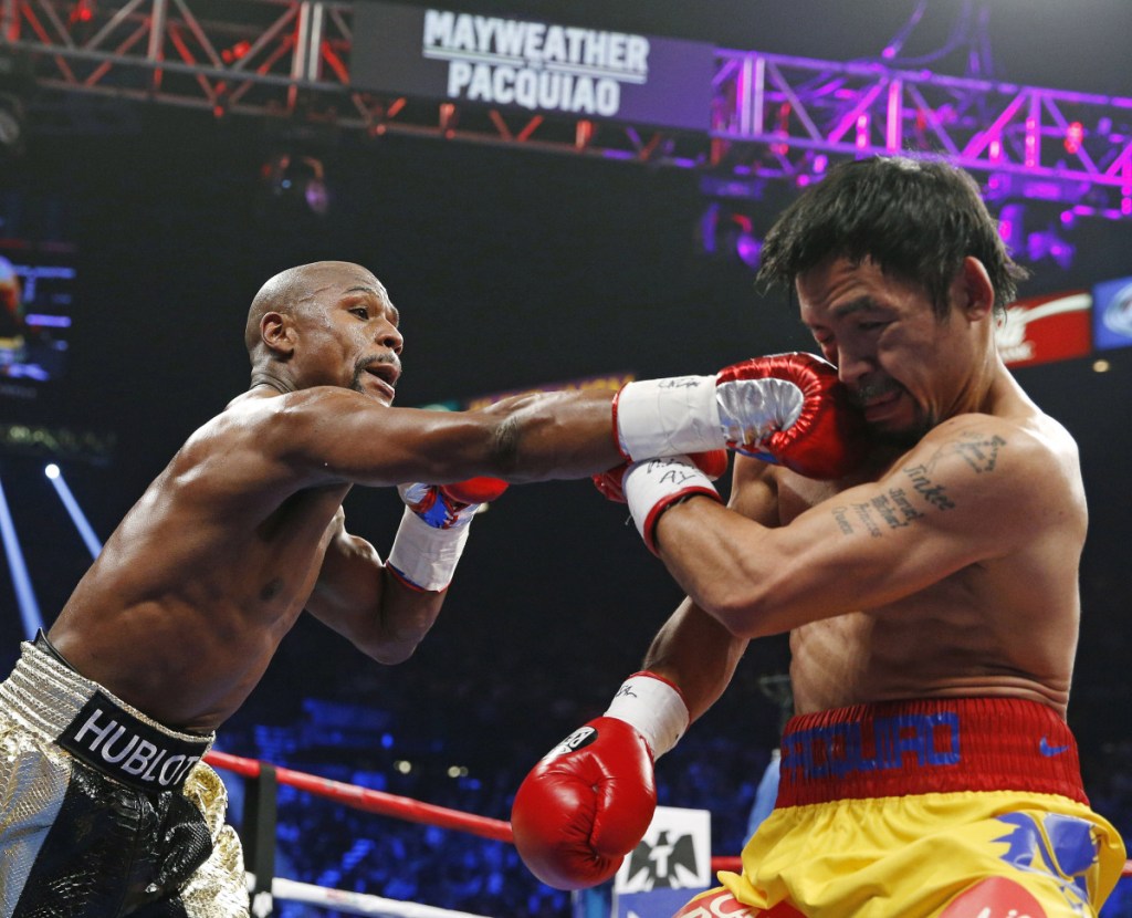 Floyd Mayweather Jr., left, connects with a right to the head of Manny Pacquiao during their welterweight title fight in May 2015 in Las Vegas. Mayweather Jr. says he's coming out of retirement again to fight Pacquiao for a second time in December. Mayweather posted a video on Instagram early Saturday that showed Pacquiao and him together, reportedly in Japan, jawing at each other over a possible second fight.