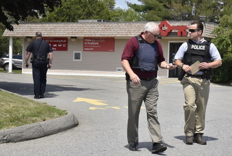Waterville police Chief Joe Massey, left, and Sgt. David Caron confer July 10 outside the KeyBank branch on Kennedy Memorial Drive in Waterville while investigating a robbery there.