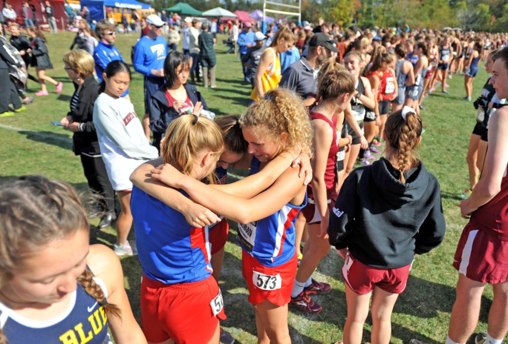 Messalonskee's Alexa Brennan, center, Charlotte Wentworth, left center, and Peyton Arbor, left, embrace at the starting line before competing in the Festival of Champions last Otober in Belfast.