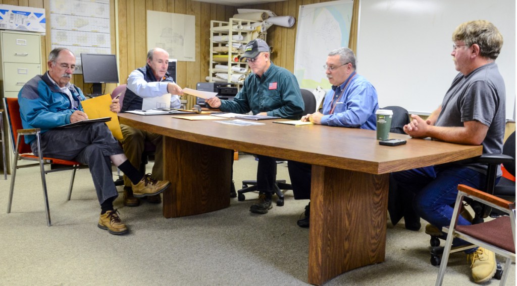 Al Hodson, left, and and Mark McCluskey, of A.E. Hodson Consulting Engineers, open bids Tuesday for construction of a Farmingdale fire station and pass them along to the station committee members — Selectman Wayne Kilgore, Assistant Fire Chief Mike LaPlante and Clerk of the Works Rick Seymour — in the Farmingdale Town Office.