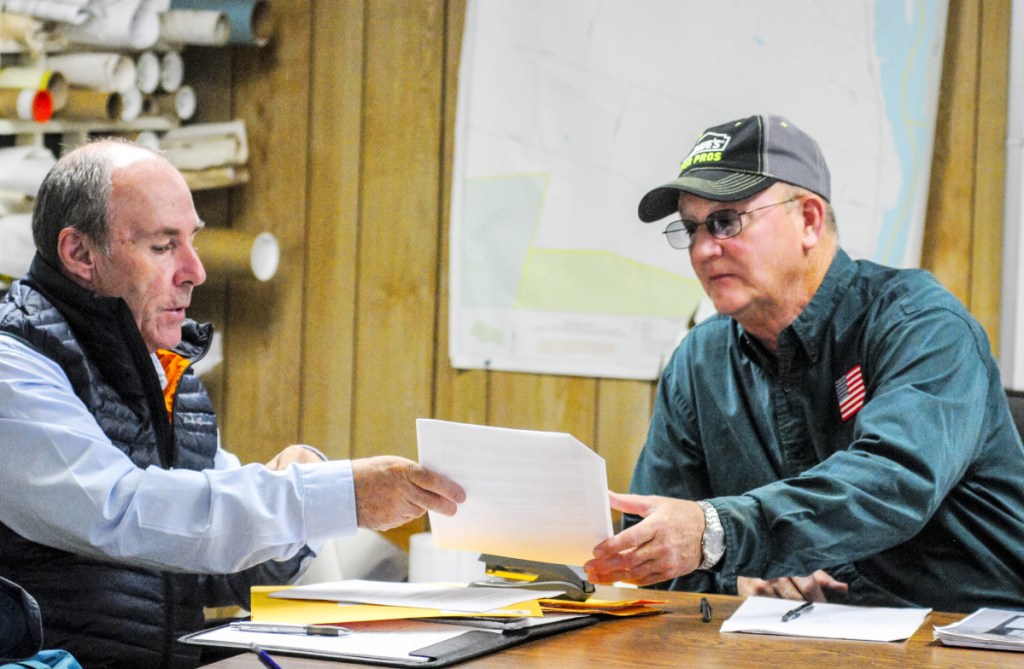Mark McCluskey, of A.E. Hodson Consulting Engineers, passes along one of the bids for construction of a Farmingdale fire station to Selectman Wayne Kilgore on Tuesday in the Farmingdale Town Office.