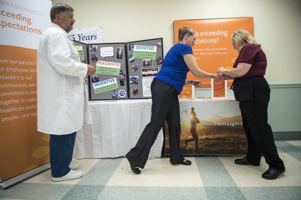 Susan Irving, far right, a dietary aide at Inland Hospital, receives information on the impending name change from communications specialist Kathy Jason as Rick Barry, a registered nurse and vice president of patient care services, looks on on Friday.