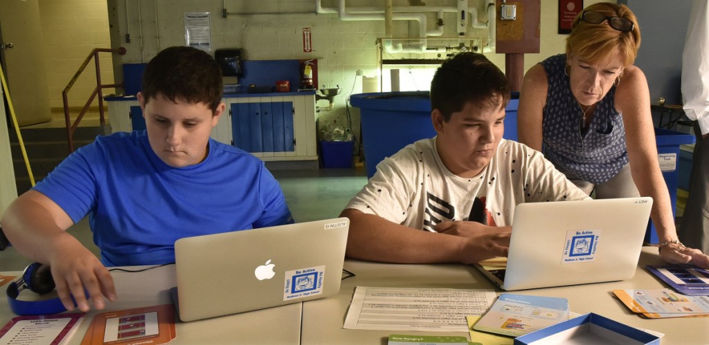 Madison Junior High School teacher Julie Wallace assists students Austin Gross, left, and Andy Paul with a computer exercise in an alternative education class on Thursday.