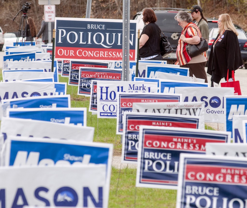 During lunch break Friday, people walk past signs outside the Augusta Civic Center during the Maine Republican Party convention. Staff photo by Joe Phelan/Staff Photographer