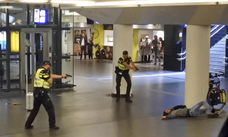 Dutch police point their guns at a wounded 19-year-old Afghan suspect who was shot by officers after allegedly stabbing two Americans in the central railway station in Amsterdam on Friday. The Americans are recovering in a hospital.