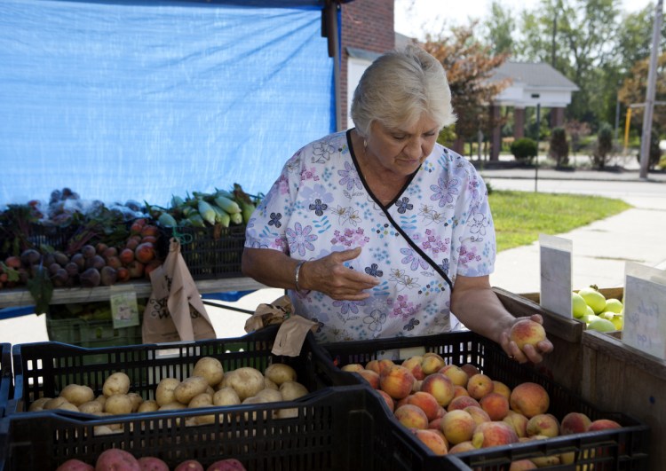 Ruth Knight, 73, of South Portland picks out produce Sunday at the farmers market in the city's Knightville neighborhood.