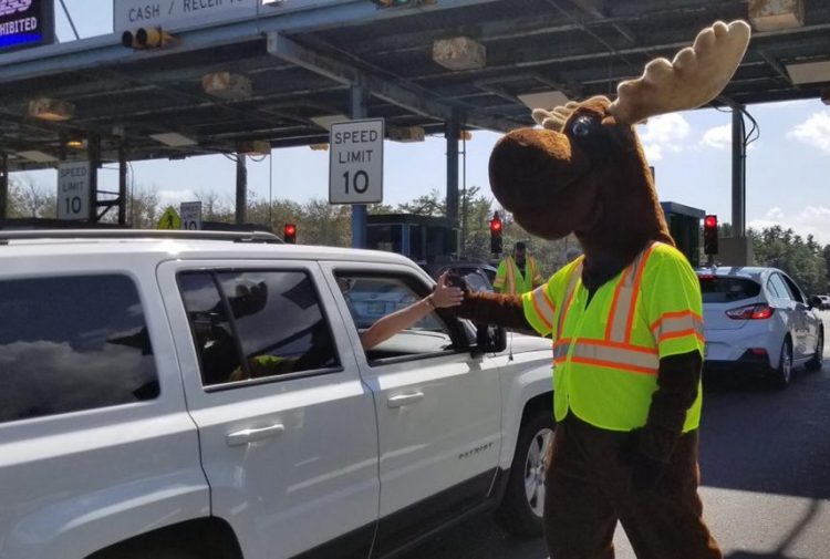 The Maine Turnpike Authority's Miles the Moose high-fives motorists as they leave Maine on Labor Day at the York Toll Plaza. Traffic was heavy but steady throughout the day on the Maine Turnpike.