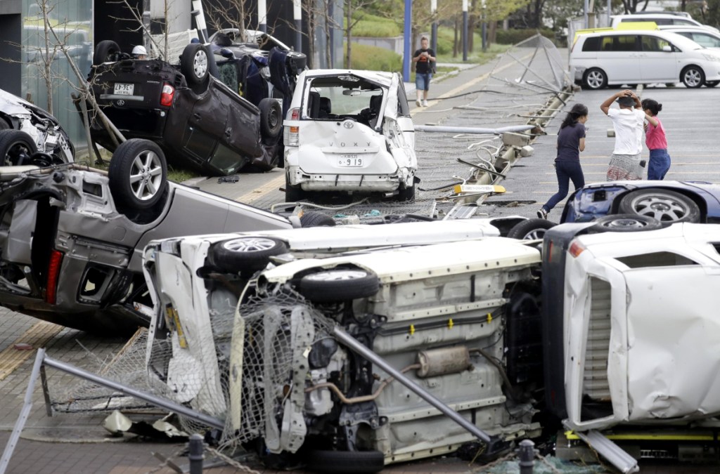 Overturned cars are seen on street following a powerful typhoon in Osaka, western Japan, Tuesday, Sept. 4, 2018. A powerful typhoon blew through western Japan on Tuesday, causing heavy rain to flood the region's main offshore international airport and high winds to blow a tanker into a connecting bridge, disrupting land and air travel.