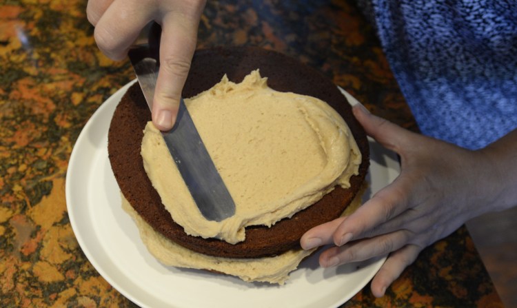 Christine Burns Rudalevige spreads peanut butter-cream cheese frosting – a family favorite – on Maine Beer Velvet Cake.