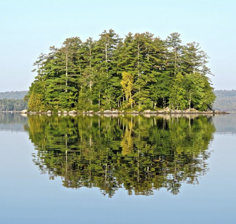 Round Island at Great Moose Lake in Hartland offers a perfect green circle mirrored in the calm water.