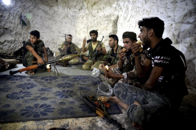Fighters with the Free Syrian Army eat in a cave where they live near the city of Idlib, Syria, last Sunday. Tens of thousands of opposition fighters await a decisive battle with government troops backed by Russia and Iran.