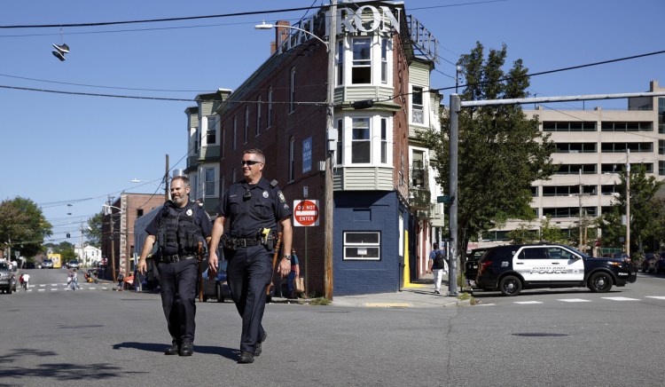 Officer Mark Keller, left, and community policing officer David Argitis cross the intersection of Alder, Oxford and Portland streets Friday. Police have expanded their presence in Bayside, the site of frequent crime and a flashpoint for discussions on the city's shelter system.