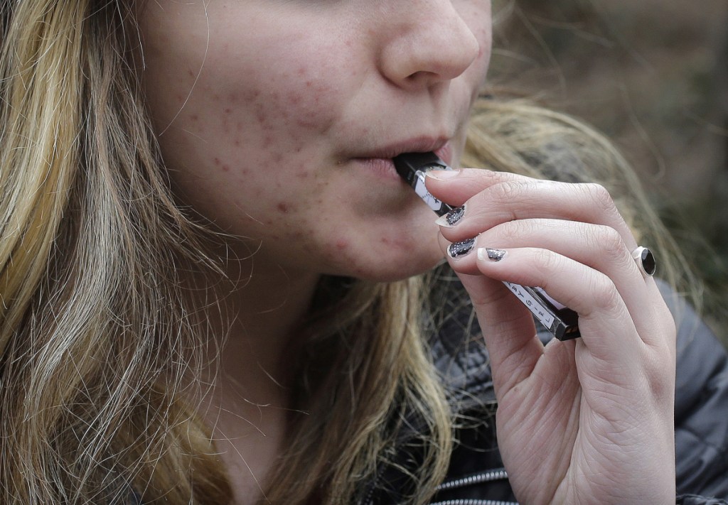 An unidentified 15-year-old high school student uses a vaping device near the school's campus in Cambridge, Mass. A school-based survey shows nearly 1 in 11 U.S. students have used marijuana in electronic cigarettes, heightening concern about the new popularity of vaping among teens. E-cigarettes typically contain nicotine, but results published Monday, Sept. 17, mean a little more than 2 million middle and high school students have used the devices to get high. (AP Photo/Steven Senne, File)