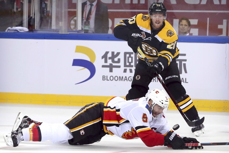 Joakim Nordstrom of the Bruins shoots on goal past Mark Giordano of the Flames during the third period Wednesday in Beijing, China. Boston beat Calgary, 3-1.