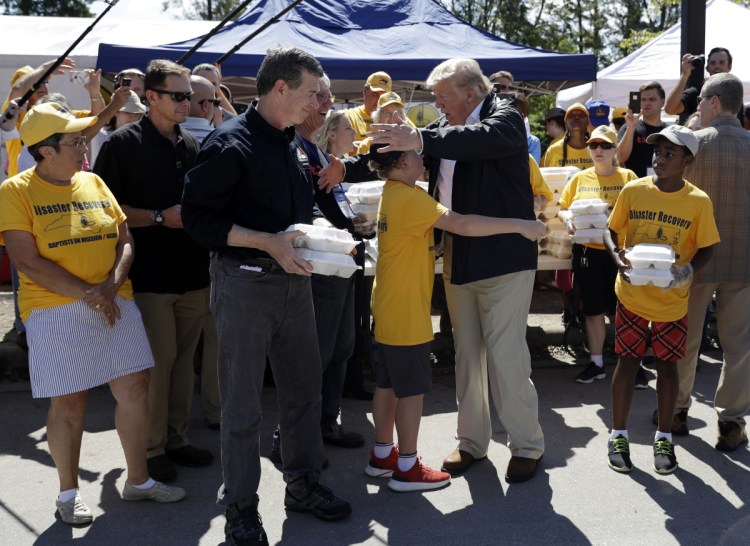 President Trump and North Carolina Gov. Roy Cooper, left, greet volunteers Wednesday as they prepare to hand out food at Temple Baptist Church in New Bern, N.C., where food and other supplies are being distributed during Hurricane Florence recovery efforts.