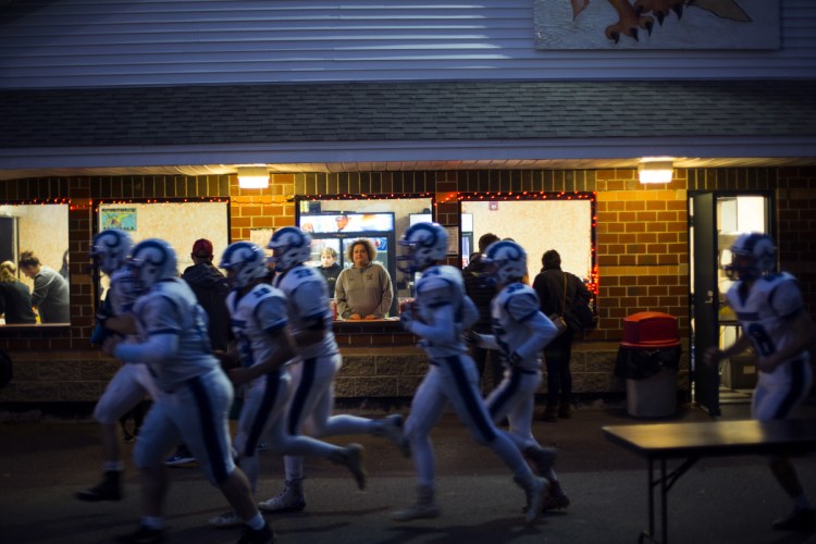 Volunteers work at the concession stand at Brunswick High School on Sept. 21, while visiting Kennebunk players run to the field.