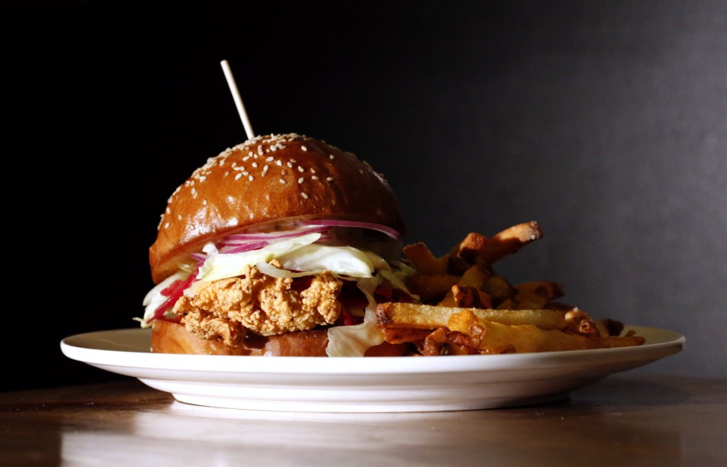 The crispy chicken sandwich is topped with cheddar, sauerkraut, slivered onions, shredded lettuce and remoulade.