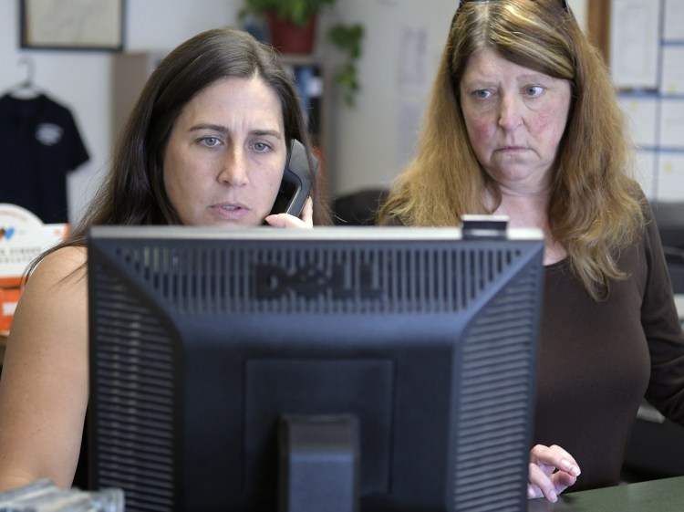 Deputy Clerk Lezley Sturtevant and Town Manager Trudy Lamoreau help a resident of Litchfield at the town office Thursday. The town lost about a month's worth of backup data when its computers crashed in July. Officials say they have now reproduced all the digital data from paper backups.