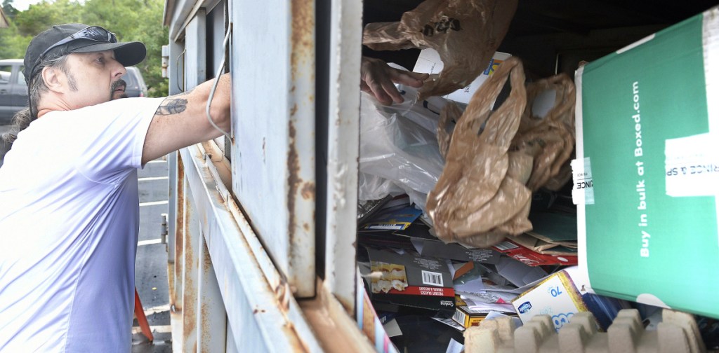 Stephen Mingo drops items into the recycling container behind the Buker Community Center on Thursday in Augusta.
