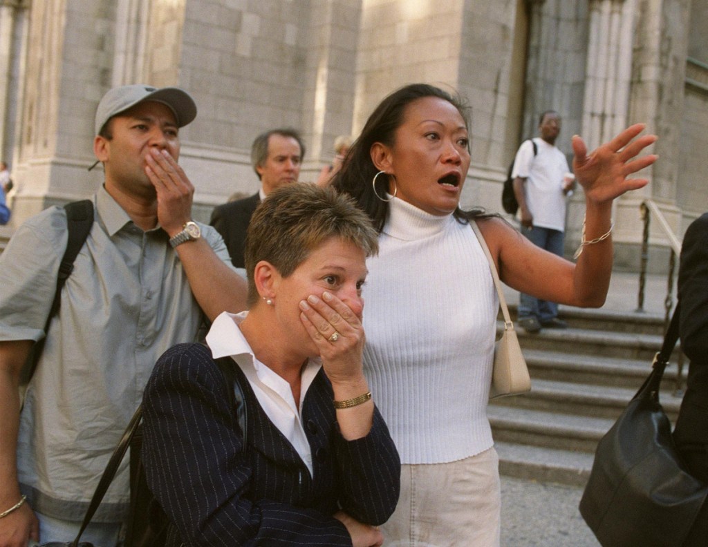 People in front of New York's St. Patrick's Cathedral react with horror as they look down Fifth Avenue towards the World Trade Center towers after planes crashed into their upper floors, in this Sept. 11, 2001 photo.