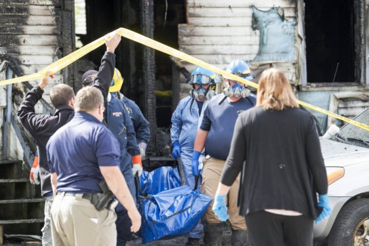 Investigators with the Office of State Fire Marshal remove the body of a man who died in a fire Friday on Milburn Street in Skowhegan.