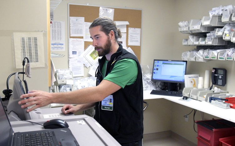 MaineGeneral Medical Center nurse Ethan Perry checks medication Wednesday at the Augusta hospital. The registered nurse said he's started working a part-time job to reduce the debt from obtaining his nursing degree.