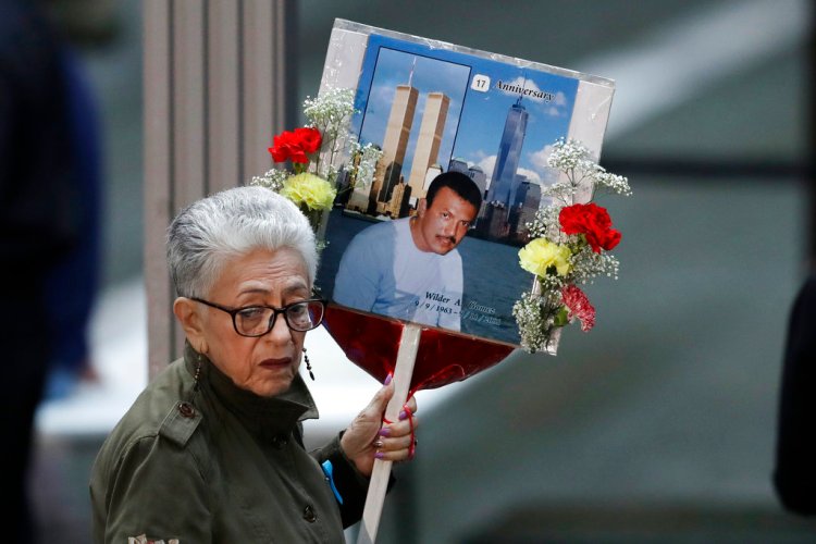 A woman arrives with a sign bearing photo memories for Wilder Gomez at the 17th anniversary of the terrorist attacks on the United States, Tuesday, Sept. 11, in New York. Gomez, from Colombia, was a bartender at Windows on the World on the 103rd floor of the World Trade Center when it was attacked. 