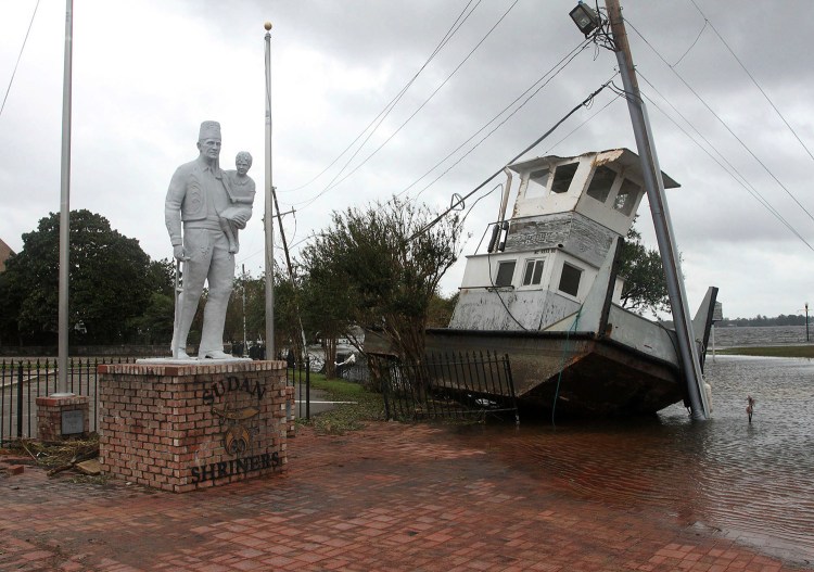 A tug boat sits next to a Shriner's Temple statue on East Front Street in New Bern, N.C., on Saturday. The boat washed up from the Neuse River with storm surge and debris from Hurricane Florence. 