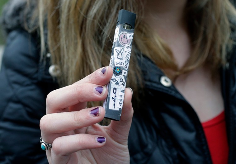 An unidentified 15-year-old high school student displays a vaping device near her school's campus in Cambridge, Mass. in April.