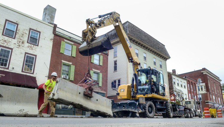 Construction workers remove Jersey barriers from the middle of Water Street on Tuesday in downtown Hallowell.