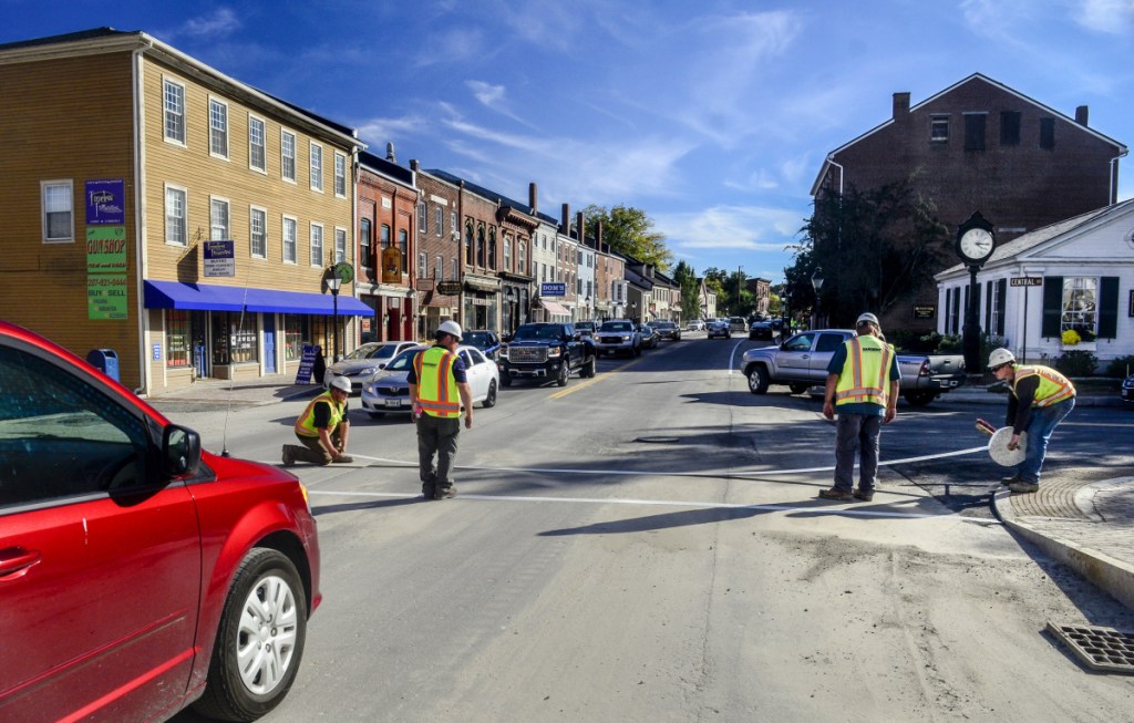Workers put reflective tape in the crosswalk on Friday at corner of Central and Water Streets in downtown Hallowell. Traffic is flowing in both directions again after both lanes were reopened just before 3 p.m.