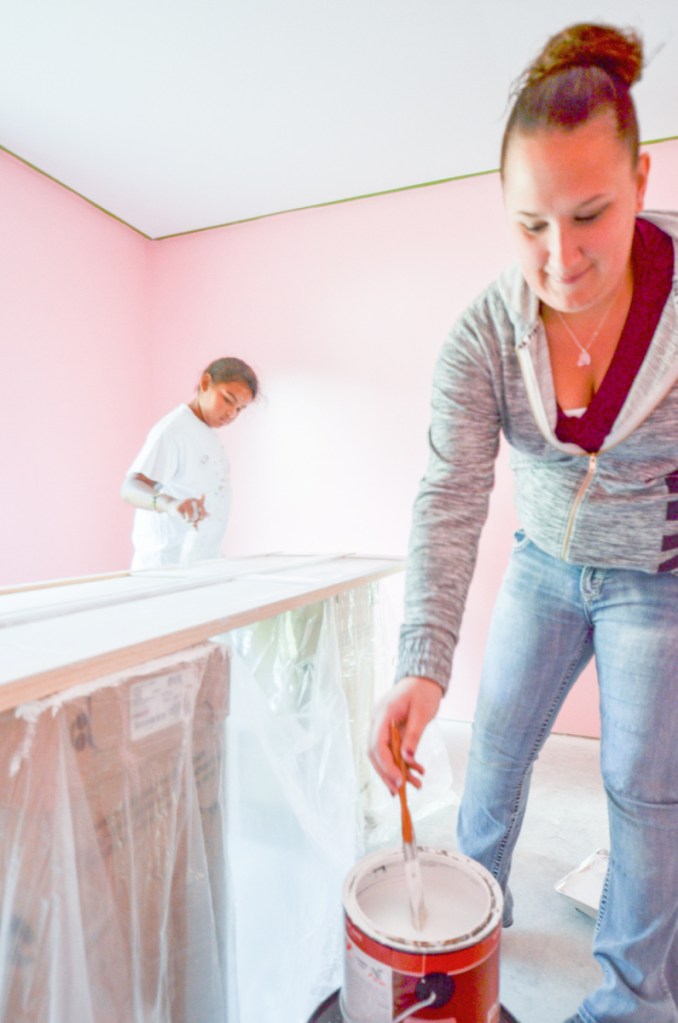 Alyssa Bofia, 10, of Waterville, left, helps Maggie Lebrun of Waterville paint closet doors at a new Waterville Area Habitat for Humanity house on Clark Street recently. Lebrun is the new owner and plans on moving in with her two children this fall.