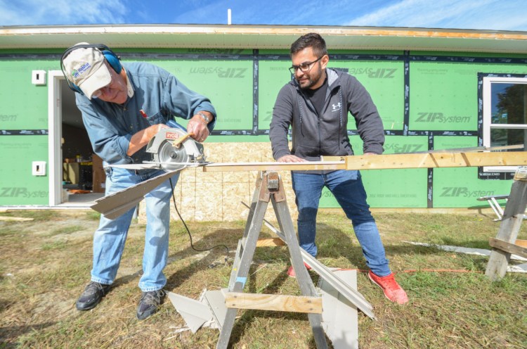 Roland Rancourt, left, of Shawmut, and Mert Ozsaydi, of Waterville, measure and cut siding recently for installation on a house being built by Waterville Area Habitat for Humanity.
